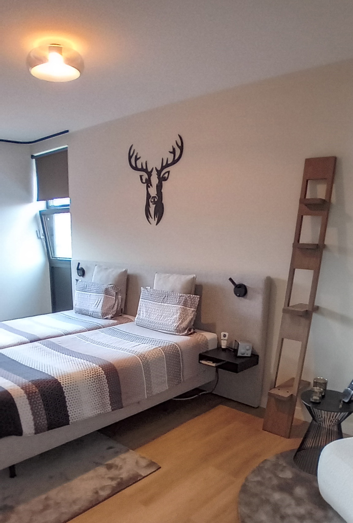 Slaapkamer waarin de wand achter het bed rustig blijft en het textiel de sfeer maakt