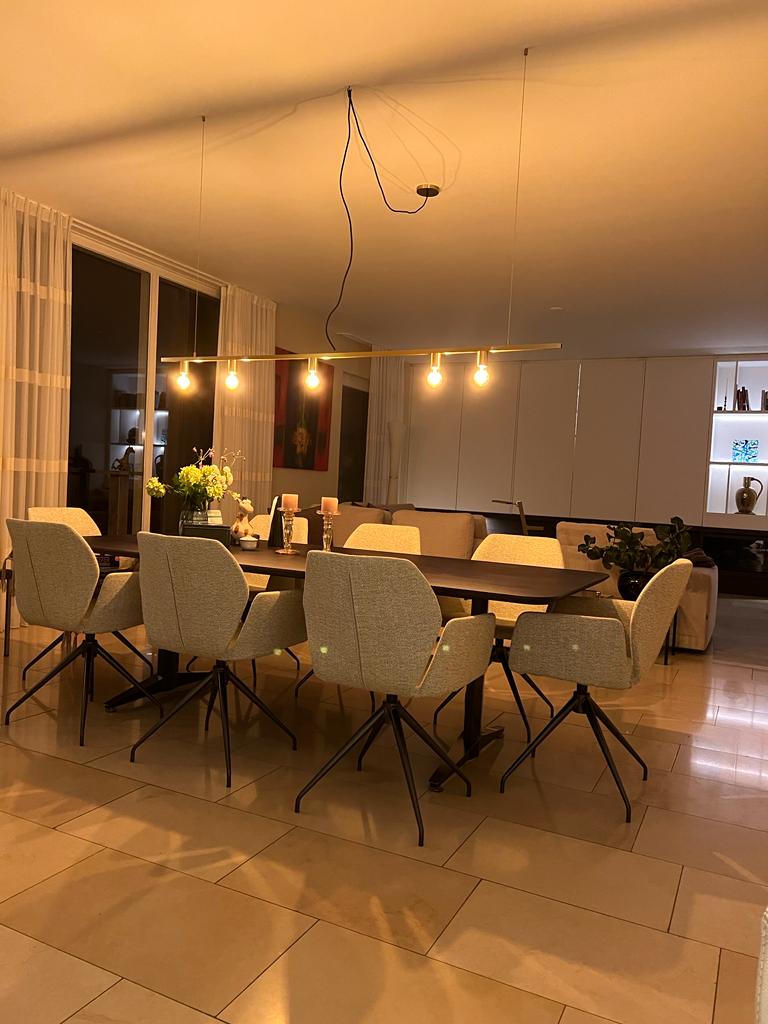 Woon- en eetkamer in één ruimte, met een tafel, stoelen en een zithoek op de achtergrond