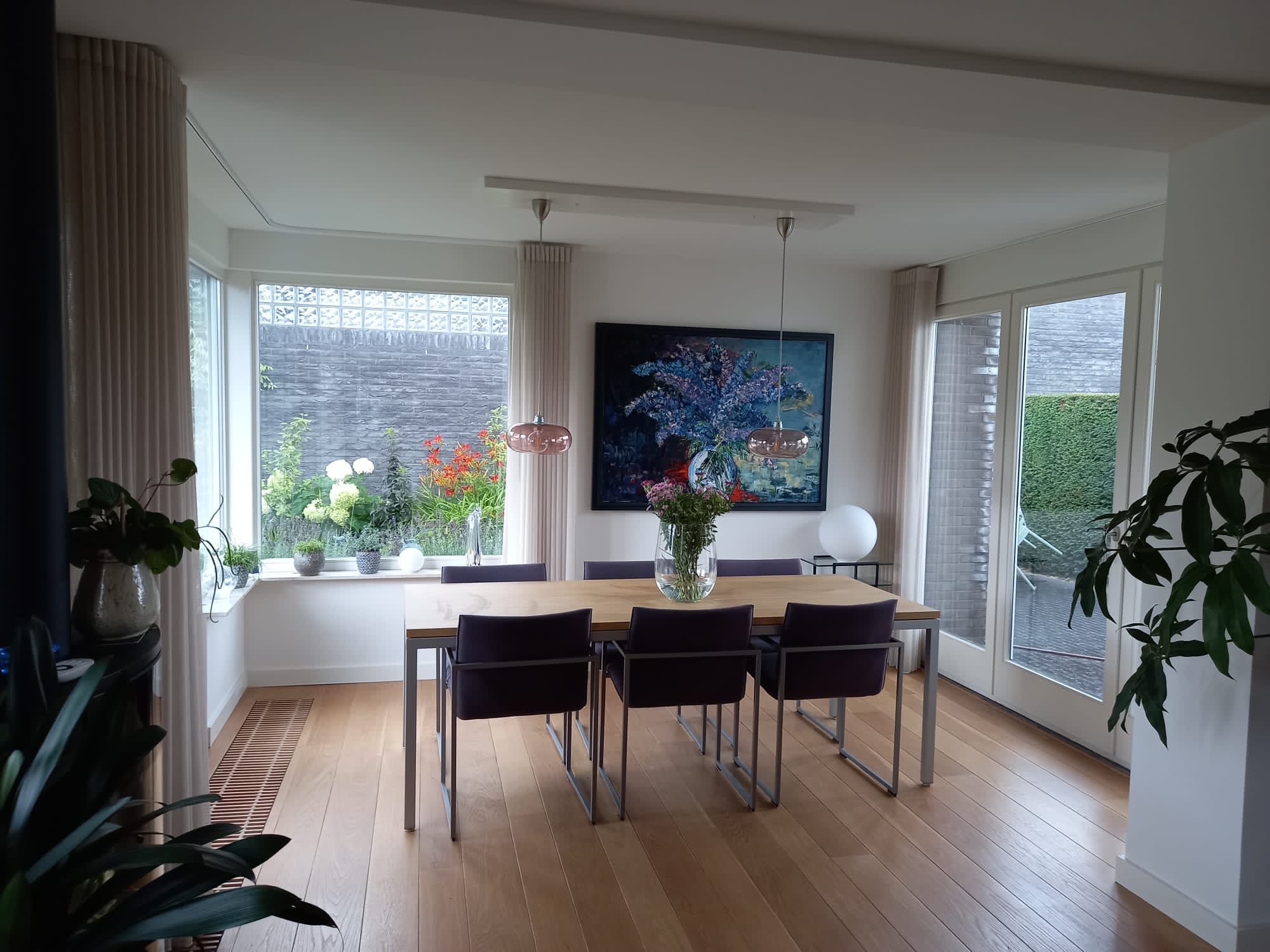 Eethoek met een houten tafel, gestoffeerde stoelen en een hanglamp erboven