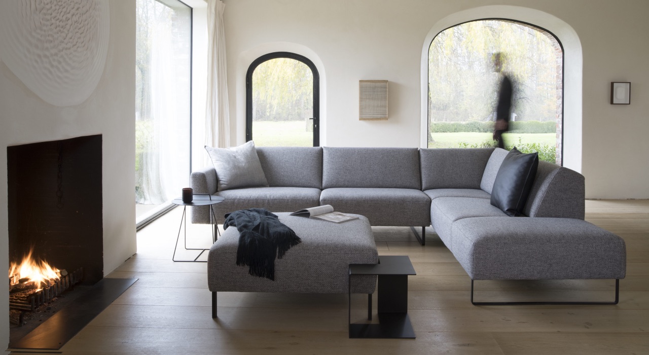 Woonkamer met een ruime bank, vloerkleed en warme kleuraccenten