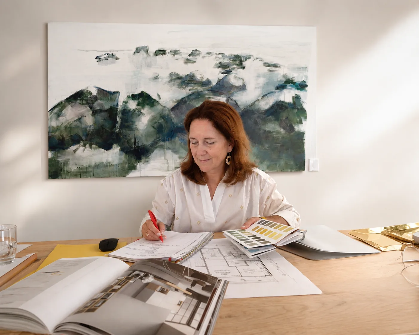 Yvette werkt aan een plattegrond met kleurstalen en materiaalmonsters op tafel